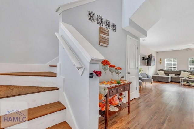 stairway with ceiling fan and wood-type flooring