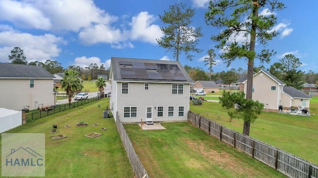 back of house with solar panels, a patio area, a yard, and central AC