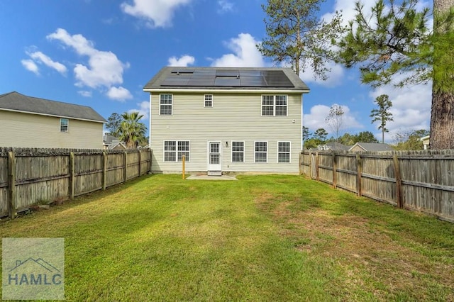 back of property with a yard and solar panels