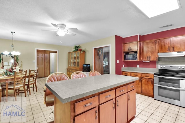 kitchen with ceiling fan with notable chandelier, hanging light fixtures, electric range, a textured ceiling, and a kitchen island