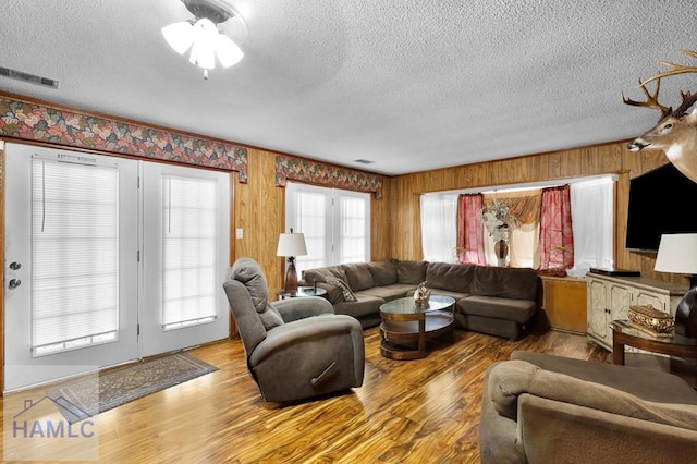 living room with wood-type flooring, a textured ceiling, and wood walls