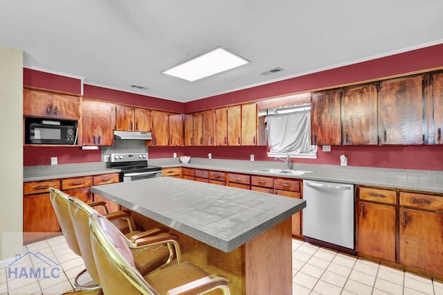 kitchen featuring sink, a center island, a kitchen bar, light tile patterned floors, and appliances with stainless steel finishes