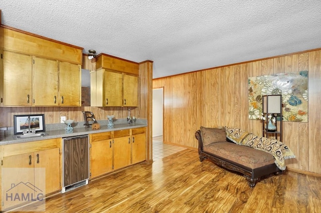 kitchen with dishwasher, light hardwood / wood-style flooring, wooden walls, and sink