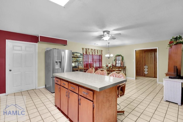 kitchen with ceiling fan with notable chandelier, light tile patterned floors, stainless steel refrigerator with ice dispenser, and a kitchen island