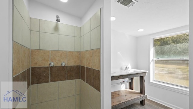 bathroom featuring plenty of natural light, hardwood / wood-style floors, and a tile shower