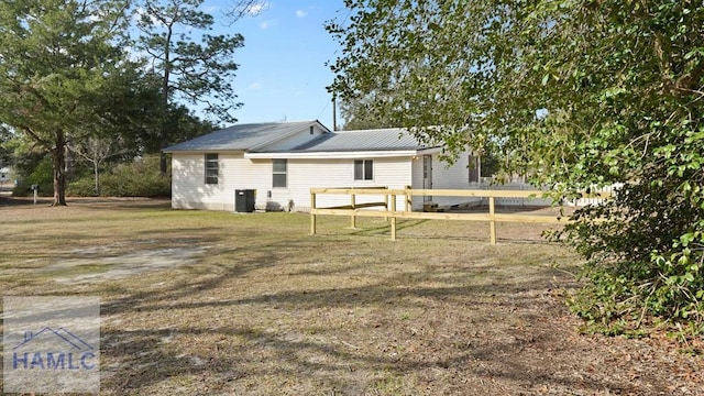 back of house with central AC and a lawn