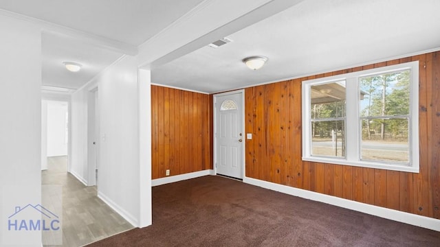 entrance foyer featuring ornamental molding, carpet, and wood walls