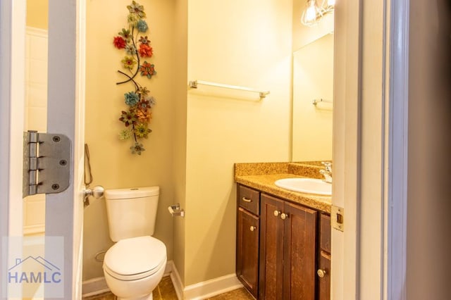 half bath featuring vanity, toilet, and baseboards