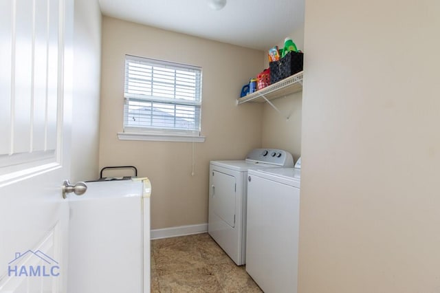 laundry area with laundry area, washing machine and dryer, and baseboards