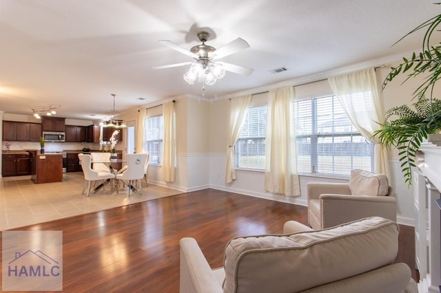 living area with a healthy amount of sunlight, light wood-type flooring, baseboards, and a ceiling fan