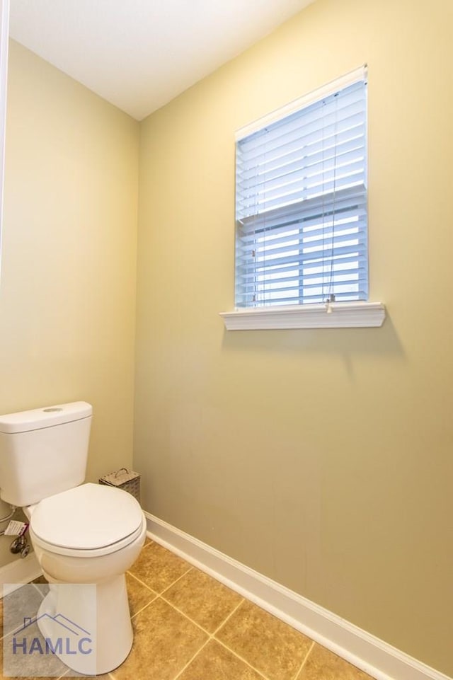 bathroom with toilet, baseboards, and tile patterned floors