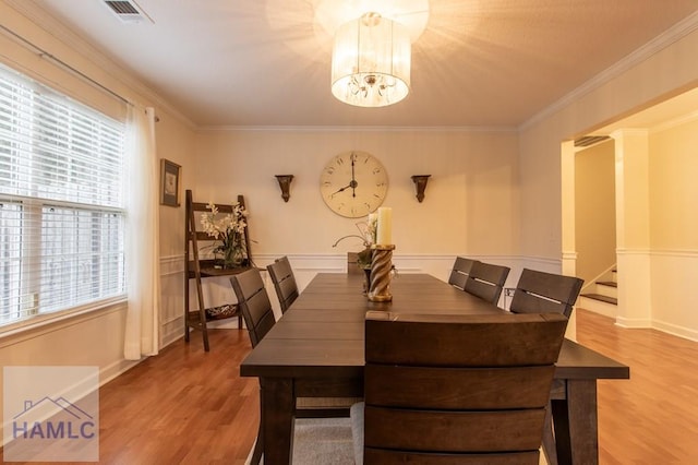 dining space featuring crown molding, wood finished floors, visible vents, and a notable chandelier