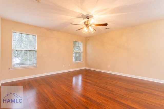 spare room featuring a ceiling fan, a healthy amount of sunlight, baseboards, and wood finished floors