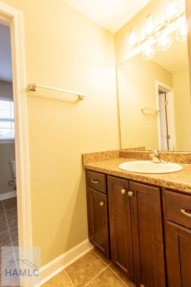 bathroom featuring toilet, vanity, baseboards, and tile patterned floors