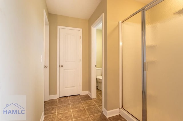 full bathroom with a stall shower, baseboards, tile patterned flooring, and toilet