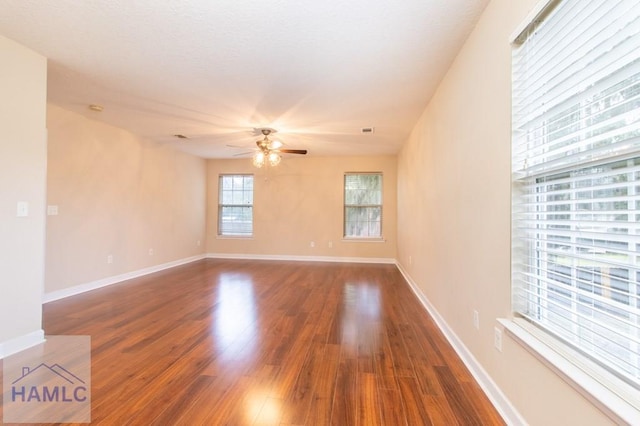 unfurnished room with ceiling fan, dark wood finished floors, and baseboards