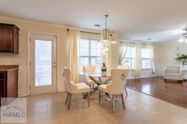 dining room with visible vents, ceiling fan with notable chandelier, ornamental molding, and light tile patterned flooring