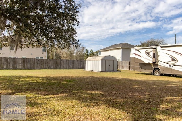 view of yard featuring an outbuilding, a fenced backyard, and a storage unit