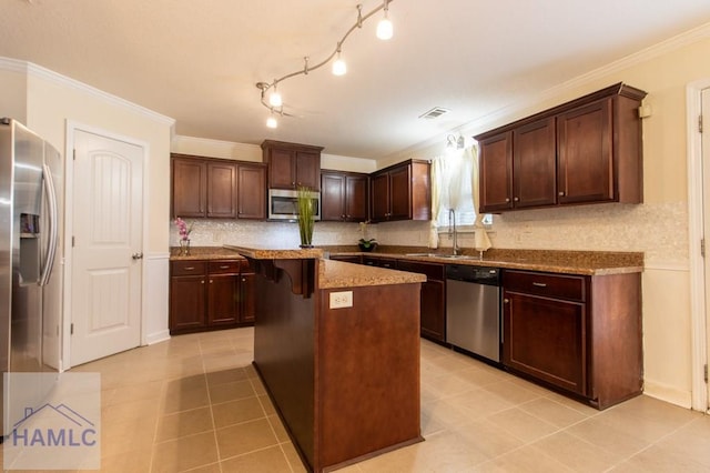 kitchen with a breakfast bar, appliances with stainless steel finishes, dark brown cabinetry, a kitchen island, and a sink