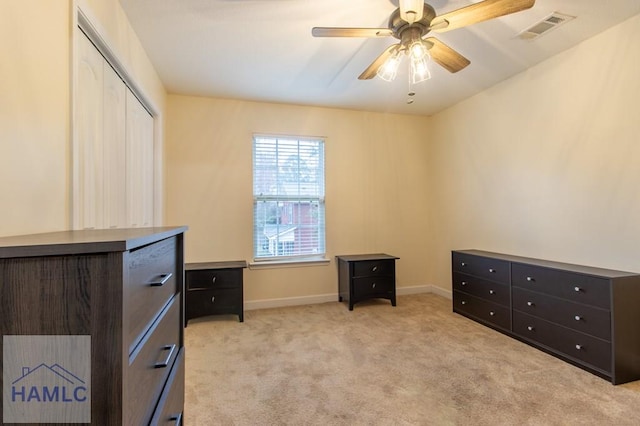 interior space with a closet, visible vents, a ceiling fan, light carpet, and baseboards