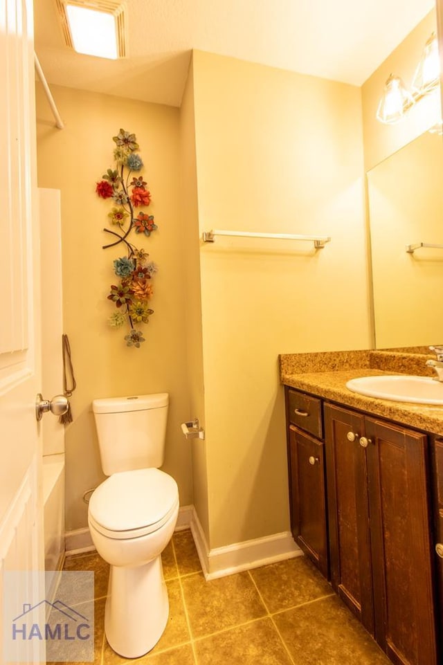 bathroom featuring baseboards, toilet, a bathing tub, tile patterned floors, and vanity