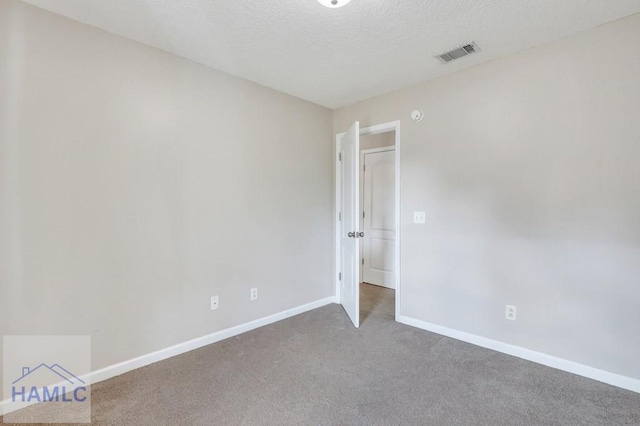 carpeted empty room with a textured ceiling