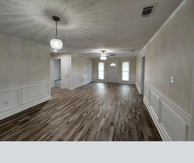 unfurnished living room featuring crown molding, dark hardwood / wood-style flooring, a textured ceiling, and ceiling fan with notable chandelier