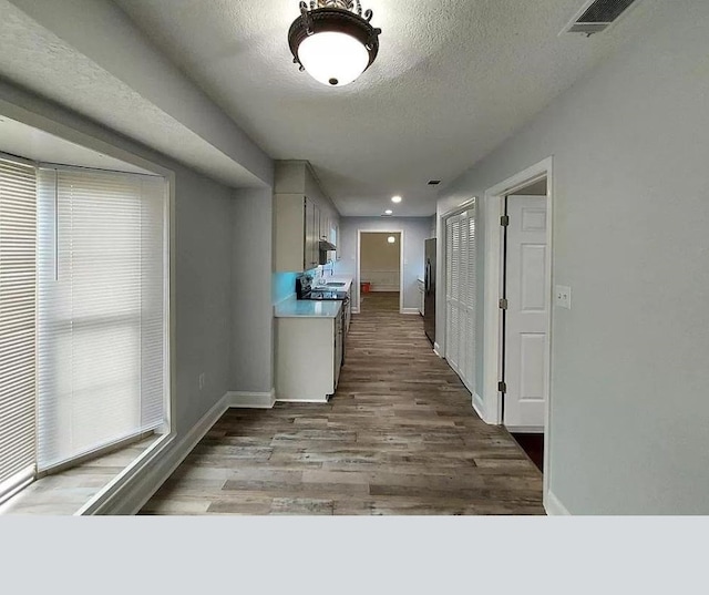 hallway featuring light hardwood / wood-style floors and a textured ceiling