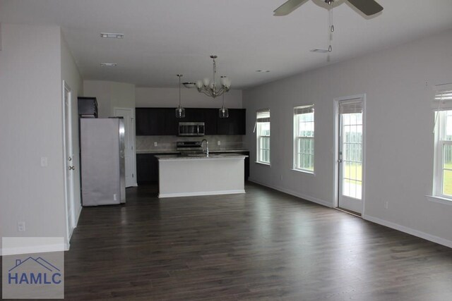 kitchen featuring dark hardwood / wood-style floors, a healthy amount of sunlight, a kitchen island with sink, and stainless steel appliances