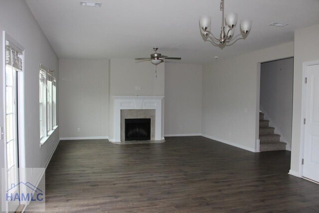 unfurnished living room featuring ceiling fan with notable chandelier and dark hardwood / wood-style floors