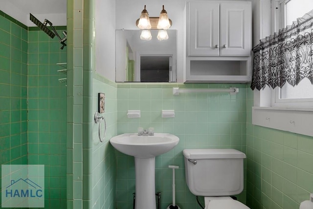 bathroom featuring a sink, tile walls, and toilet