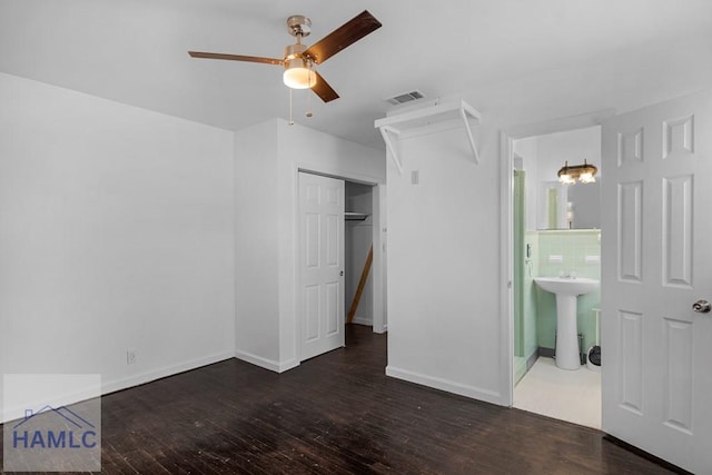 unfurnished bedroom featuring baseboards, visible vents, ensuite bath, wood finished floors, and a sink