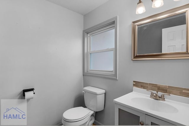 bathroom featuring toilet, tasteful backsplash, and vanity