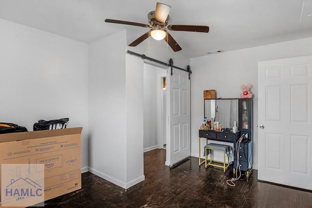 interior space with baseboards, a barn door, visible vents, and wood finished floors