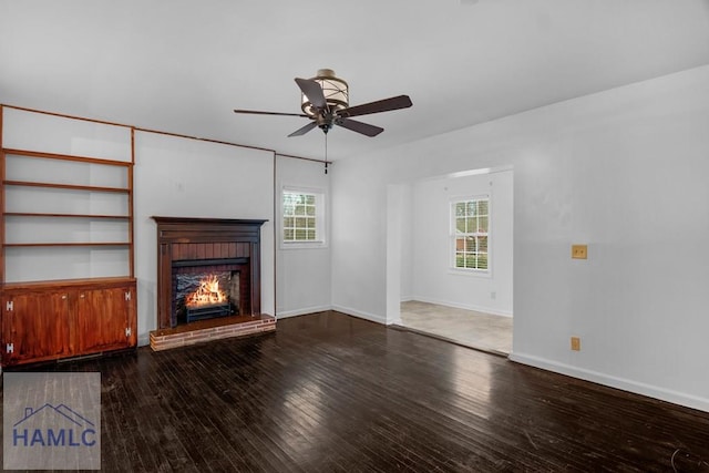 unfurnished living room with ceiling fan, a fireplace, hardwood / wood-style flooring, and baseboards