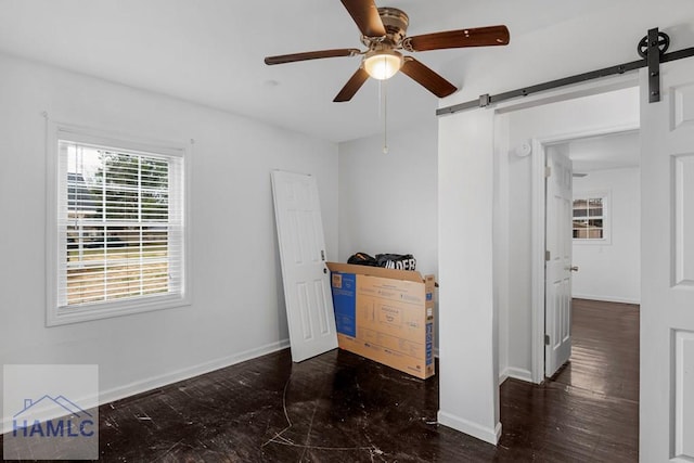 bedroom with a barn door, a ceiling fan, and baseboards