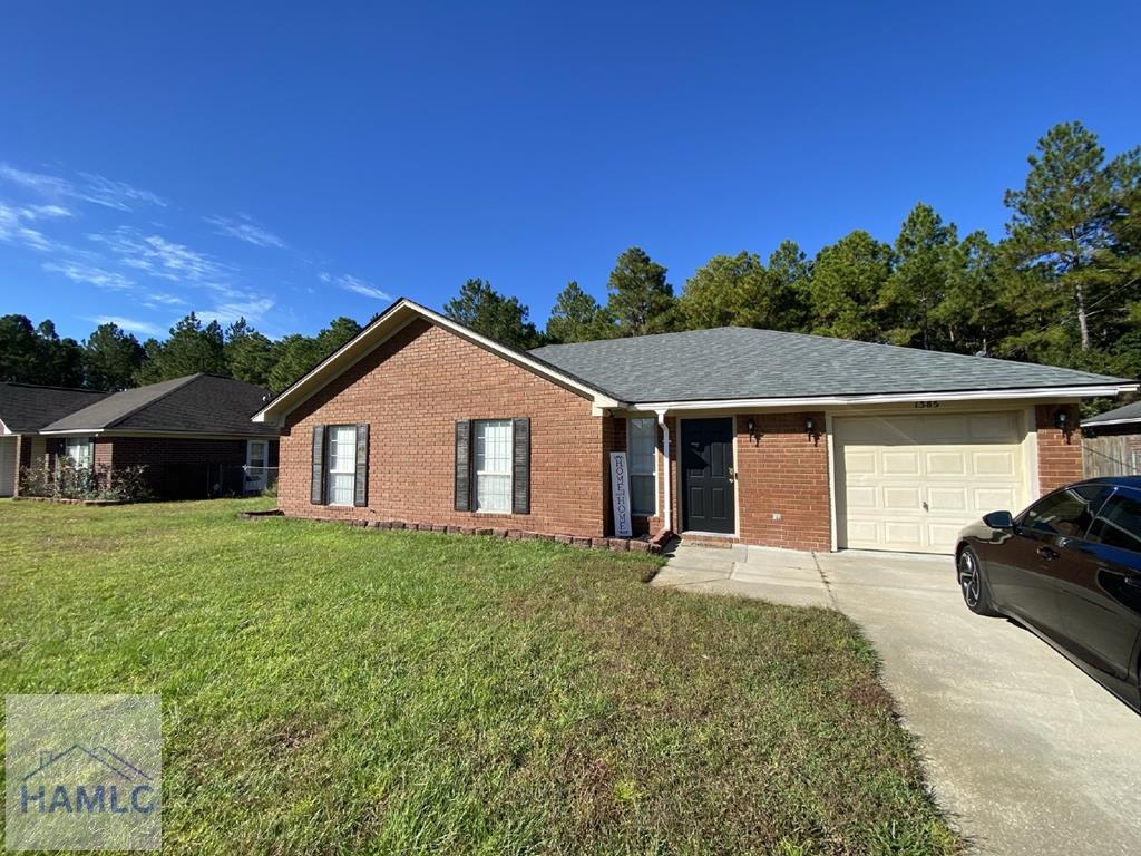 ranch-style home with driveway, a garage, a front lawn, and brick siding