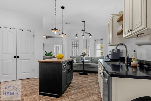 kitchen featuring a center island, dark countertops, a sink, dark cabinets, and dishwasher