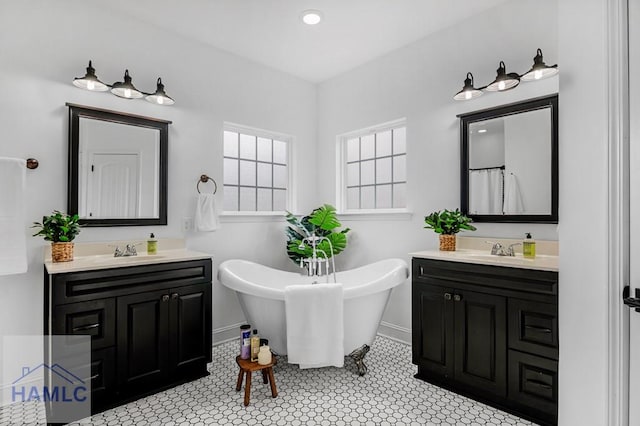 full bath featuring a freestanding tub, two vanities, and a sink