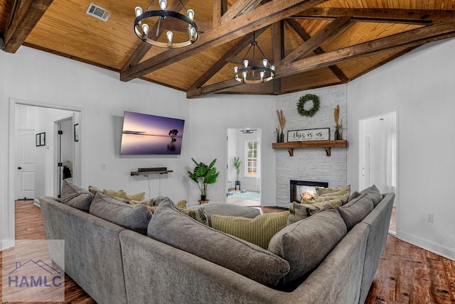 living room featuring visible vents, wooden ceiling, wood finished floors, a fireplace, and a notable chandelier