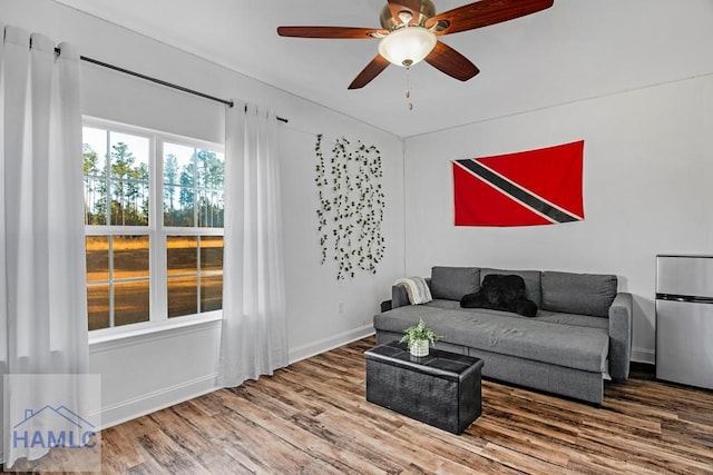 living room featuring ceiling fan, baseboards, and wood finished floors