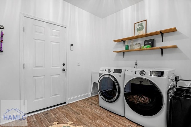 clothes washing area featuring laundry area, washer and dryer, and wood finished floors