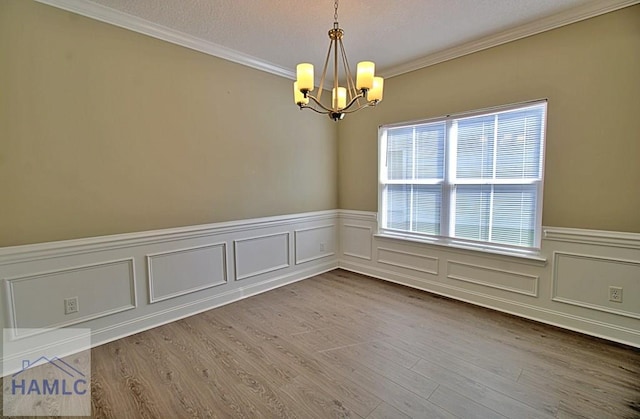587 Fairview Cir, Hinesville, GA 31313 - unfurnished room with a chandelier, crown molding, wainscoting, wood finished floors, and a decorative wall