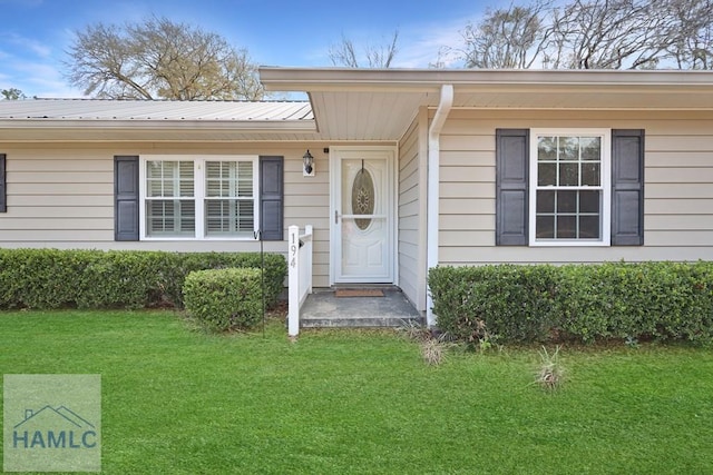 doorway to property featuring metal roof and a yard