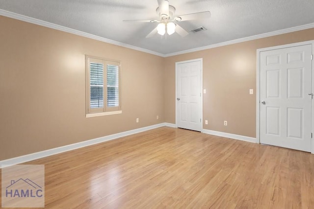 unfurnished room featuring ceiling fan, light wood-style flooring, visible vents, baseboards, and ornamental molding