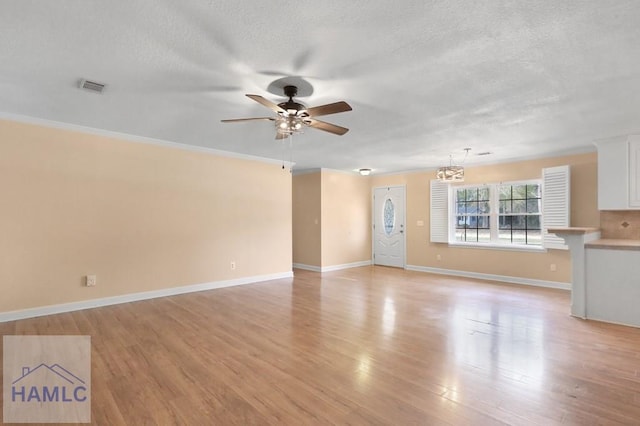 unfurnished living room featuring a textured ceiling, ceiling fan with notable chandelier, visible vents, baseboards, and light wood finished floors