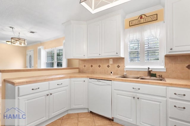 kitchen with white dishwasher, a peninsula, a sink, visible vents, and a healthy amount of sunlight