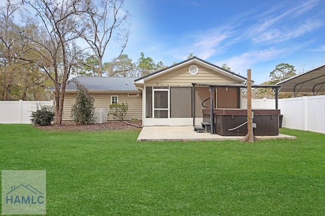 rear view of house featuring a hot tub, a sunroom, a fenced backyard, metal roof, and a yard