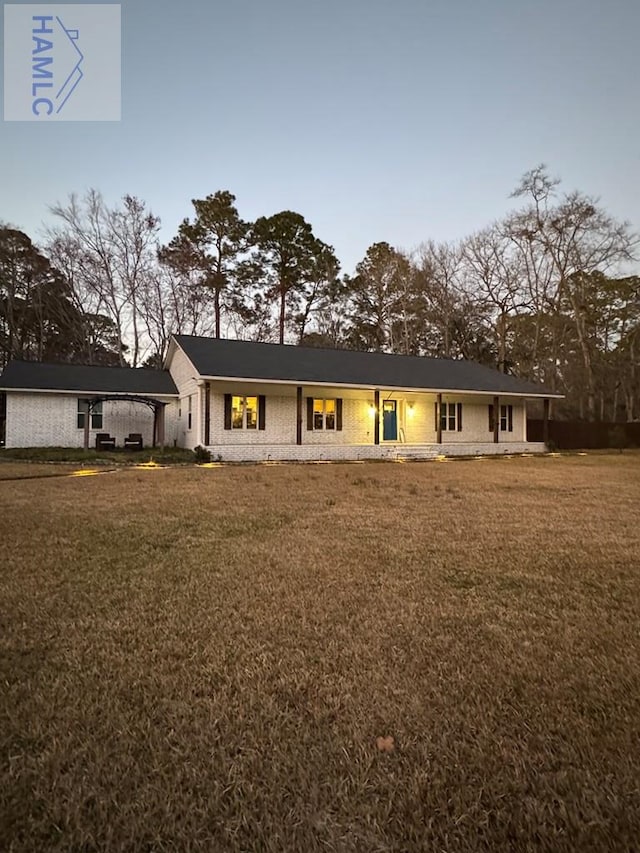 view of front facade with a front lawn, an attached carport, and brick siding