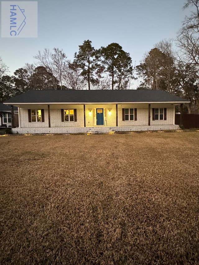 rear view of house featuring a lawn and brick siding